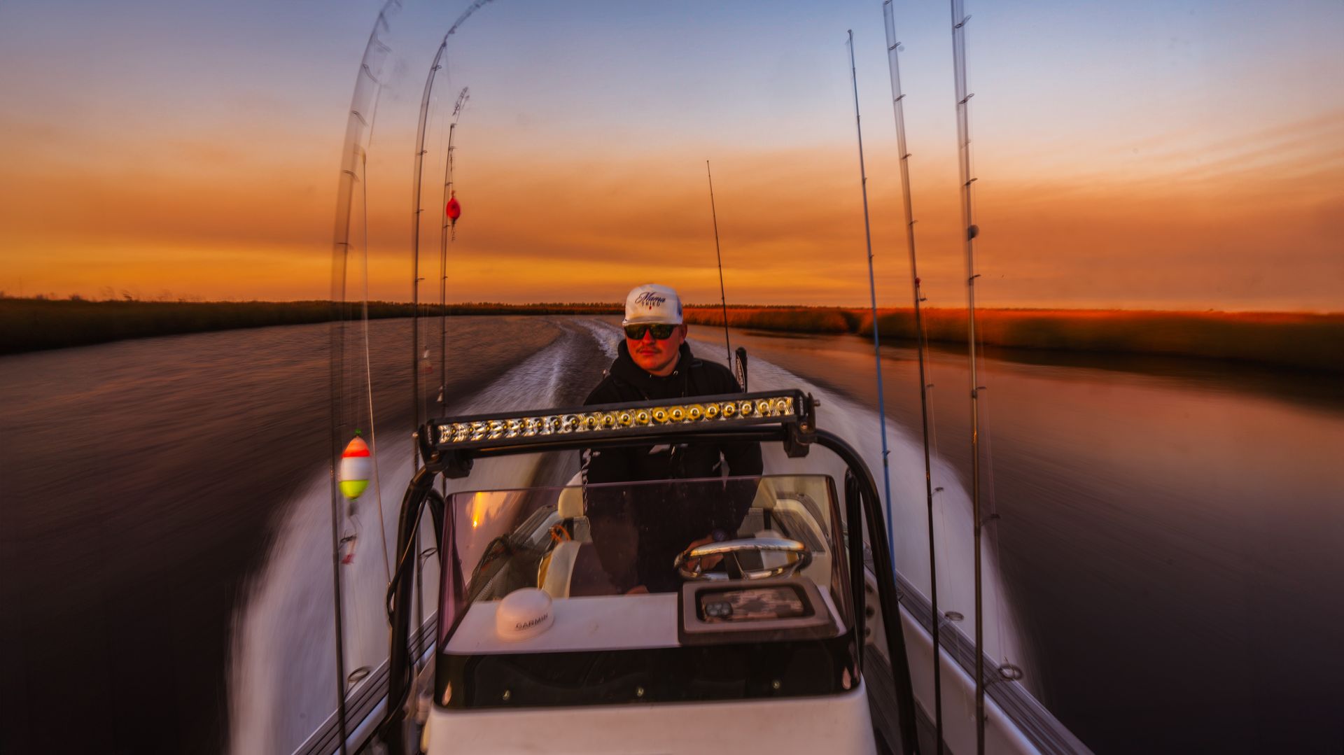 Captain driving boat at sunset with fishing rods